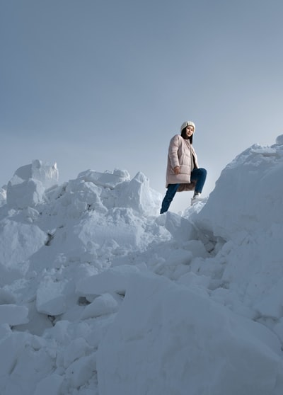 女人穿着白色夹克和蓝色牛仔裤站在白雪覆盖的地面白天

